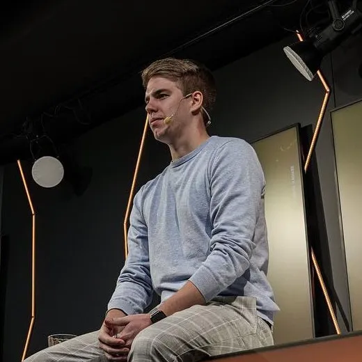 Michal Kabele sedí na pódiu studia s mikroportem